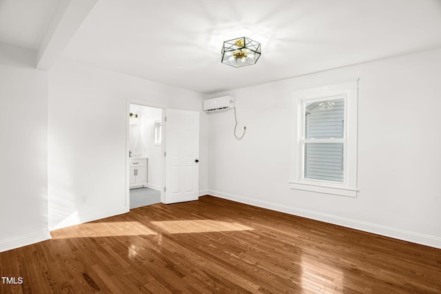 unfurnished room with hardwood / wood-style floors, a wall mounted AC, and beam ceiling