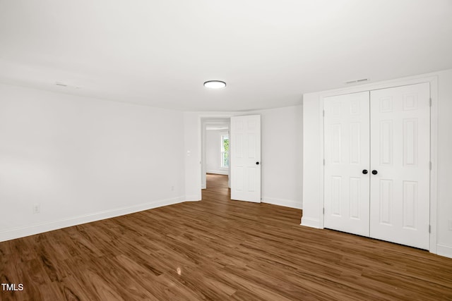 unfurnished bedroom with dark hardwood / wood-style floors and a closet