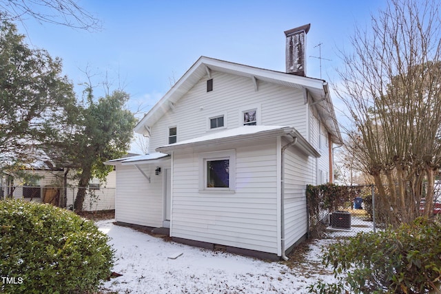 snow covered house featuring central AC unit