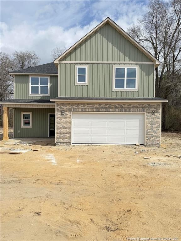 view of front facade with board and batten siding, brick siding, and driveway