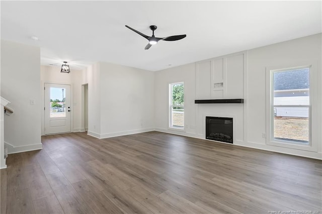 4935 High Branch Ct, Stedman, NC 28391 - unfurnished living room with a wealth of natural light, a ceiling fan, a glass covered fireplace, and wood finished floors