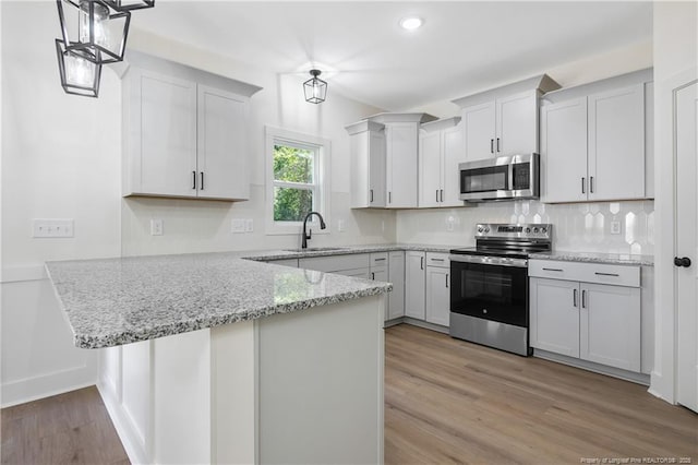 4935 High Branch Ct, Stedman, NC 28391 - kitchen with a peninsula, light wood finished floors, a sink, stainless steel appliances, and light stone counters