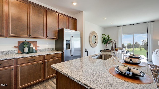 kitchen with sink, light stone counters, dark hardwood / wood-style floors, and stainless steel fridge