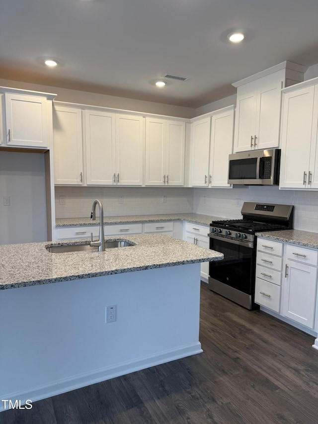 kitchen featuring light stone countertops, white cabinets, dark wood-type flooring, stainless steel appliances, and sink