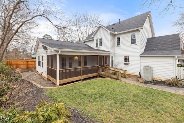 rear view of property featuring a deck, a sunroom, and a yard