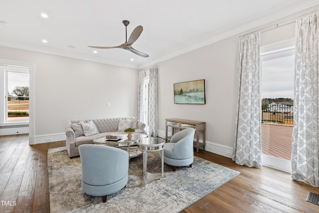 living room featuring ceiling fan, ornamental molding, and wood-type flooring