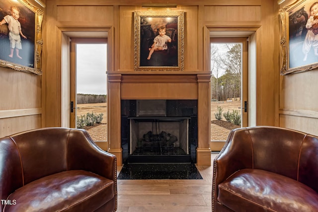 living area with hardwood / wood-style flooring, a large fireplace, and wood walls