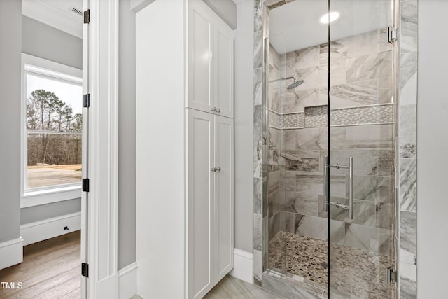 bathroom with crown molding, wood-type flooring, and walk in shower