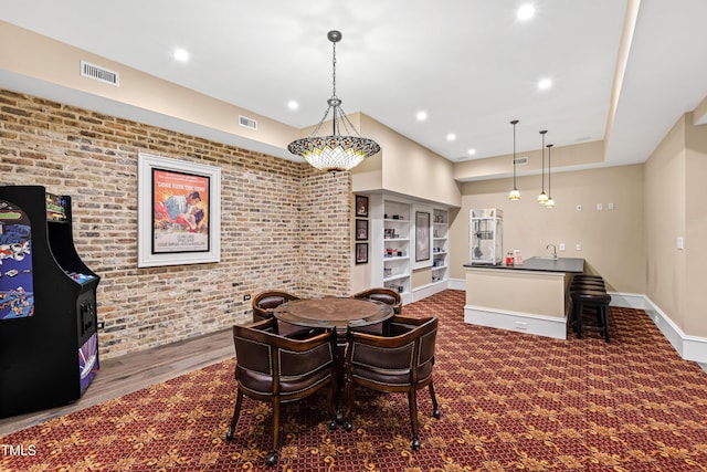 dining space featuring sink, dark carpet, and brick wall