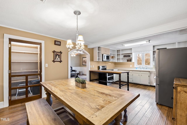 dining area featuring crown molding, sink, a textured ceiling, and light wood-type flooring