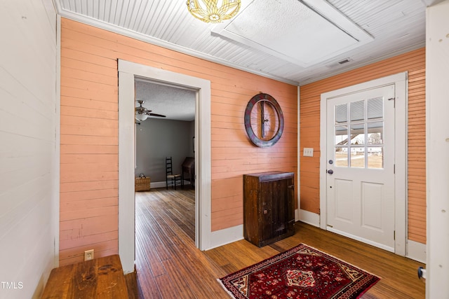 entryway featuring dark wood-type flooring, wooden walls, and a textured ceiling