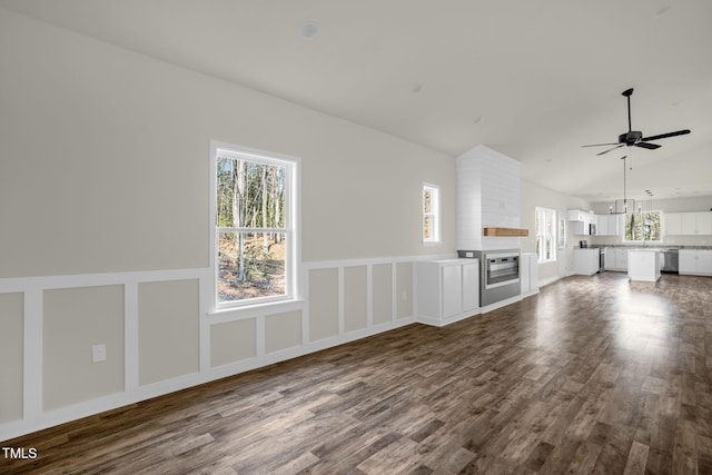 unfurnished living room featuring ceiling fan, hardwood / wood-style flooring, a fireplace, and a wealth of natural light