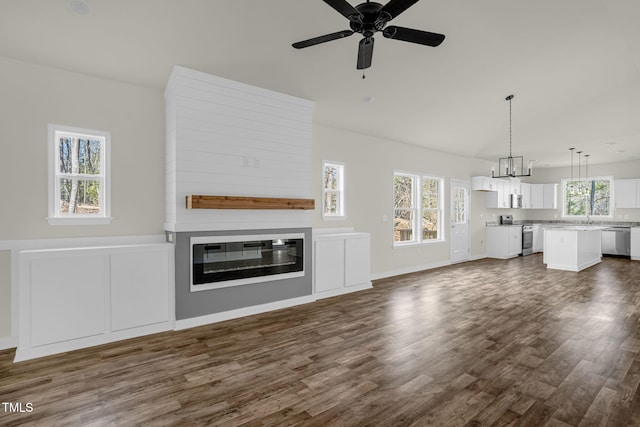 unfurnished living room featuring dark wood-type flooring, ceiling fan with notable chandelier, and a large fireplace