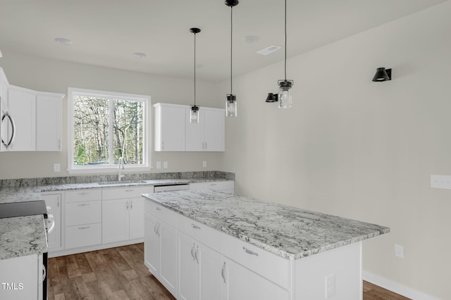 kitchen with hardwood / wood-style flooring, sink, white cabinets, and a center island