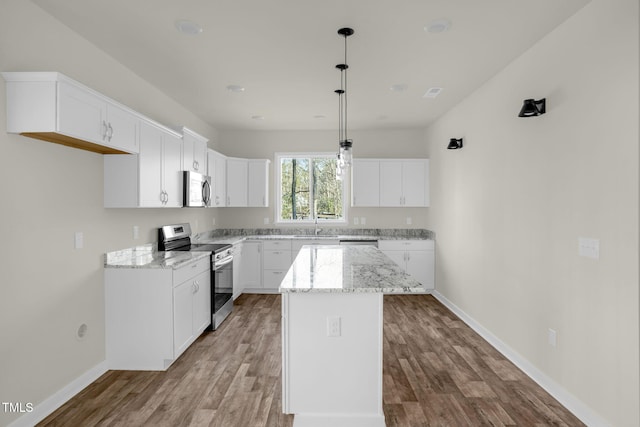 kitchen with pendant lighting, a kitchen island, white cabinetry, and appliances with stainless steel finishes