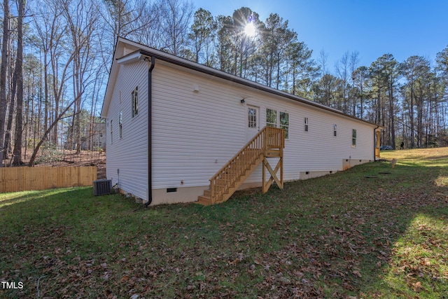 rear view of house with central AC unit and a lawn