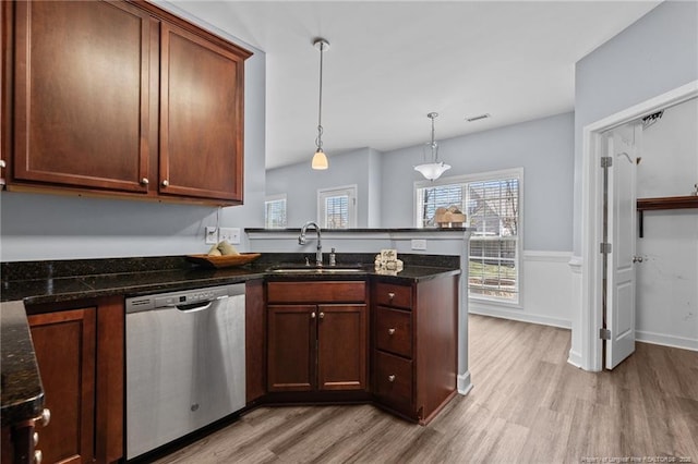 kitchen featuring light hardwood / wood-style flooring, stainless steel dishwasher, pendant lighting, sink, and dark stone countertops