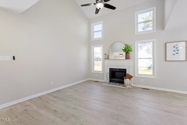 unfurnished living room featuring high vaulted ceiling, light wood-type flooring, and a wealth of natural light