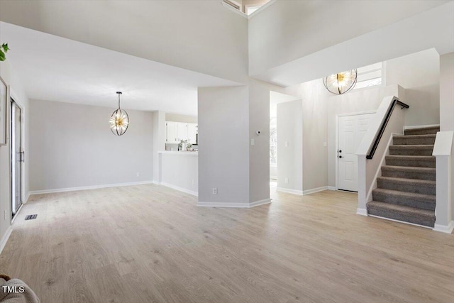 unfurnished living room with a chandelier and light hardwood / wood-style flooring