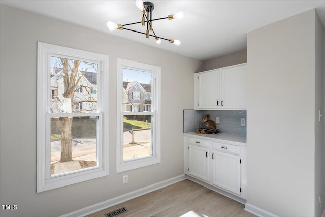 interior space with a wealth of natural light, a chandelier, and light hardwood / wood-style flooring