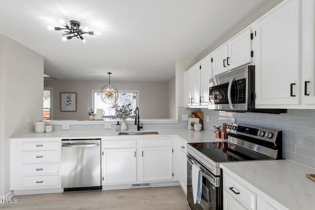 kitchen featuring stainless steel appliances, white cabinetry, sink, and pendant lighting