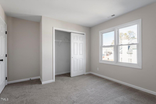 unfurnished bedroom featuring light colored carpet and a closet