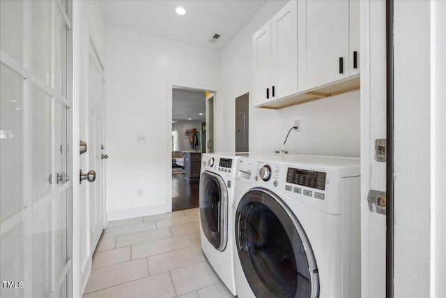 washroom featuring cabinets, separate washer and dryer, light tile patterned floors, and electric panel