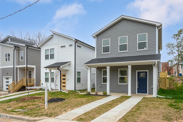 view of front of property with covered porch, a front lawn, and roof with shingles