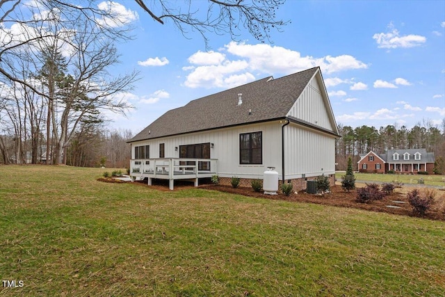 rear view of house featuring a wooden deck, central AC unit, and a lawn