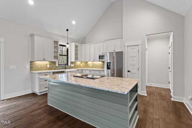 kitchen with decorative light fixtures, white cabinets, a center island, stainless steel appliances, and light stone countertops