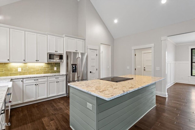 kitchen with a center island, dark hardwood / wood-style flooring, stainless steel appliances, light stone countertops, and white cabinets