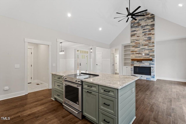 kitchen with decorative light fixtures, dark wood-type flooring, stainless steel range with electric cooktop, and an island with sink