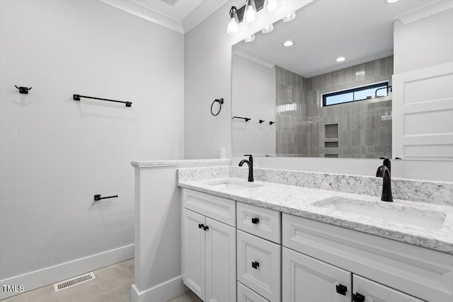 bathroom featuring tile patterned flooring, vanity, ornamental molding, and a tile shower