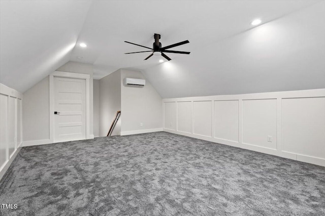 additional living space featuring lofted ceiling, ceiling fan, a wall mounted AC, and dark colored carpet