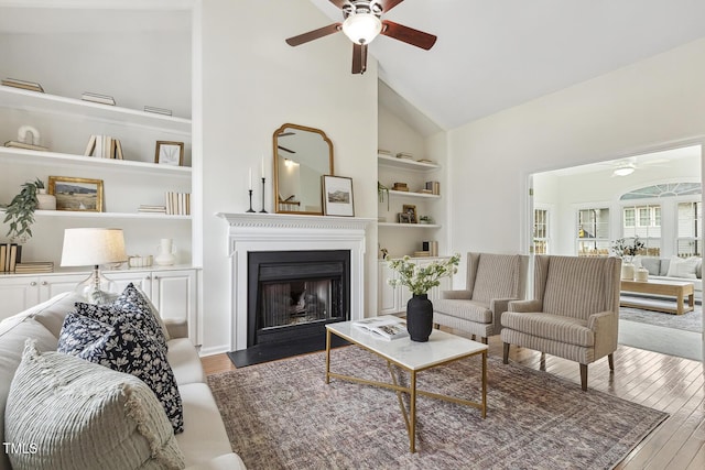 living room with high vaulted ceiling, dark wood-type flooring, ceiling fan, and built in shelves