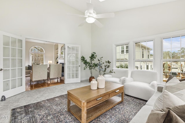 living room with high vaulted ceiling, french doors, a healthy amount of sunlight, and dark colored carpet