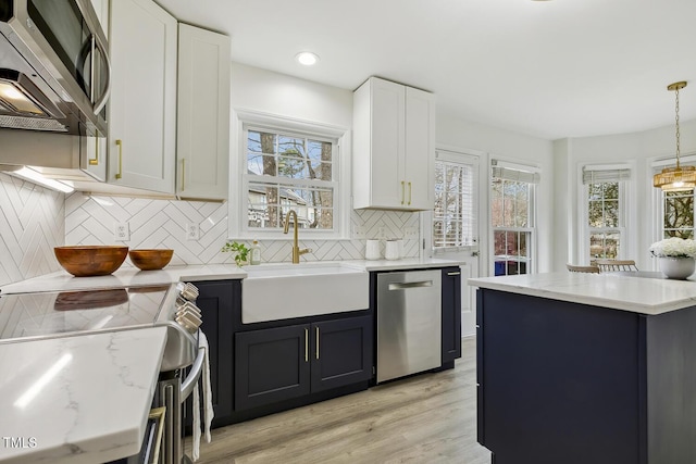 kitchen featuring sink, white cabinetry, hanging light fixtures, appliances with stainless steel finishes, and decorative backsplash