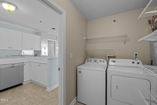 washroom with sink, a textured ceiling, ornamental molding, and separate washer and dryer