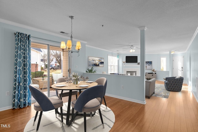 dining space featuring light hardwood / wood-style floors, crown molding, and ceiling fan with notable chandelier