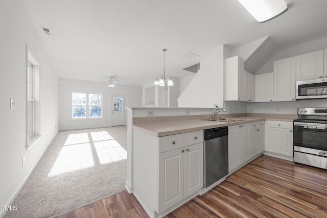 kitchen featuring a peninsula, appliances with stainless steel finishes, open floor plan, and light countertops