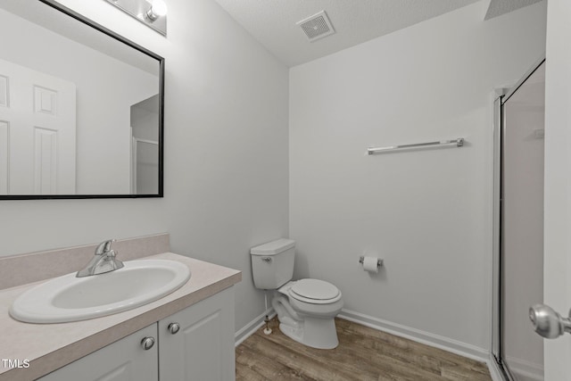 bathroom featuring visible vents, toilet, a stall shower, vanity, and wood finished floors