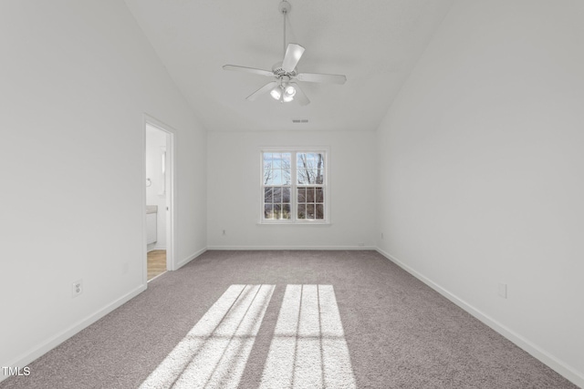 spare room with light colored carpet, vaulted ceiling, baseboards, and ceiling fan