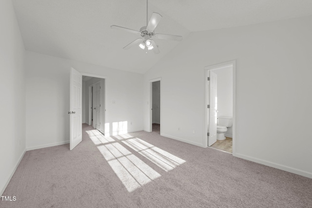 unfurnished bedroom with lofted ceiling, ensuite bathroom, a ceiling fan, light carpet, and baseboards