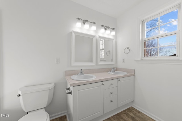 bathroom with double vanity, a sink, toilet, and baseboards