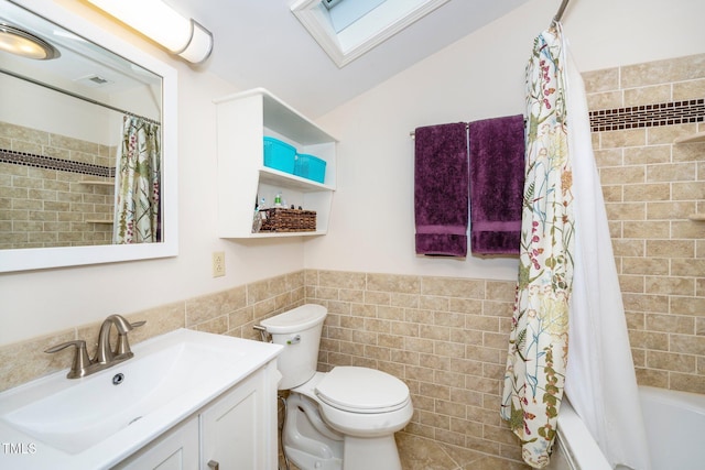 full bathroom with shower / tub combo with curtain, a skylight, tile walls, vanity, and toilet