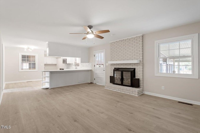 unfurnished living room featuring a fireplace, light hardwood / wood-style floors, and ceiling fan