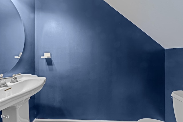 bathroom with lofted ceiling, sink, and toilet