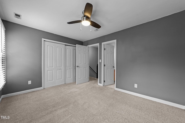 unfurnished bedroom featuring ceiling fan, light colored carpet, and a closet