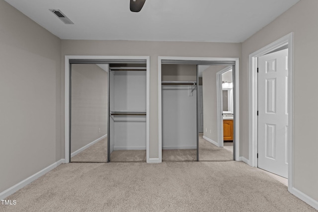 unfurnished bedroom featuring light colored carpet and multiple closets