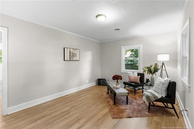 sitting room featuring light wood-type flooring and crown molding